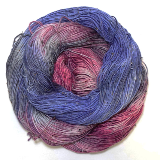 Hand-dyed tweed yarn in bold deep blue and rich raspberry with grey blending tones and subtle flecks throughout — rich, saturated, and dramatically layered.