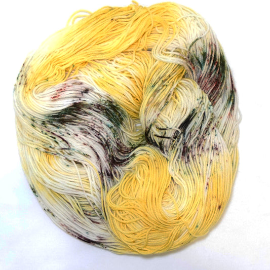 Hand-dyed yarn in rich sunflower yellow with earthy green and brown speckles — warm, grounded, and inspired by wild sunflower fields.