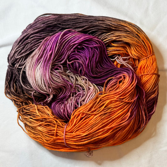 Multicolored yarn skein with purple, orange, and brown tones on a white background