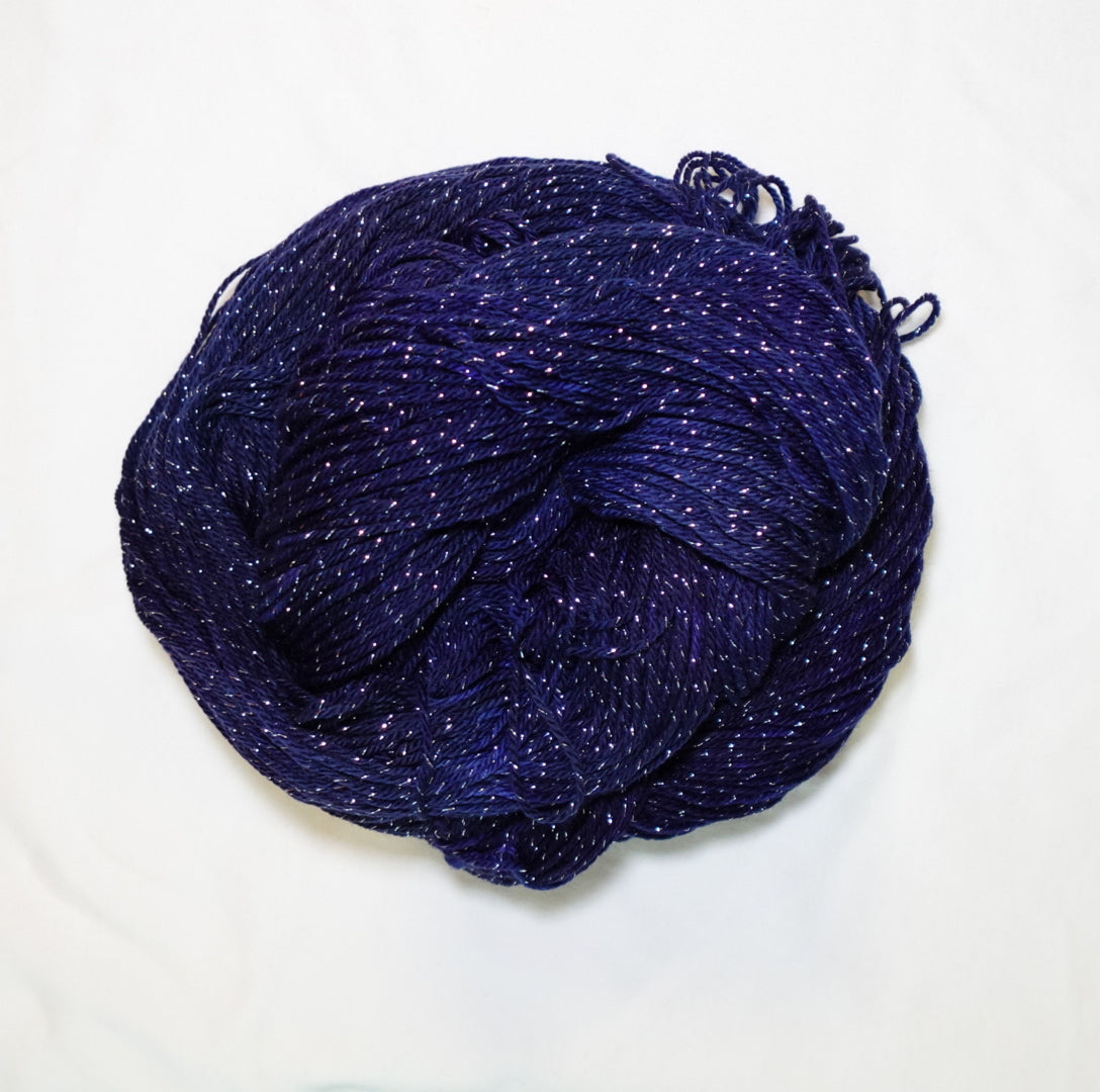 Hand-dyed silver metallic fingering weight yarn in deep navy, violet, and near-black tones with silver sparkle.